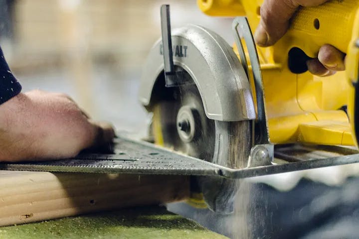 Skilled workman uses a circular saw and speed square to cut a board at a perfect right angle